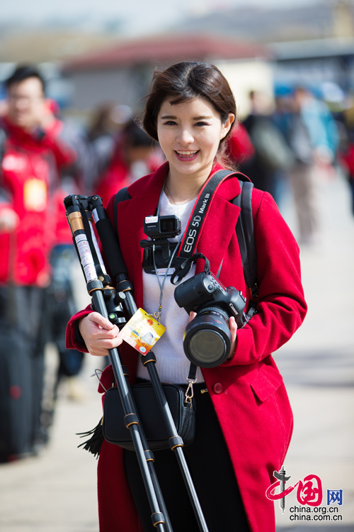 2016年兩會(huì)，人民大會(huì)大堂前，一位笑容燦爛的紅衣女記者正步入大會(huì)堂。中國(guó)網(wǎng) 鄭亮 攝